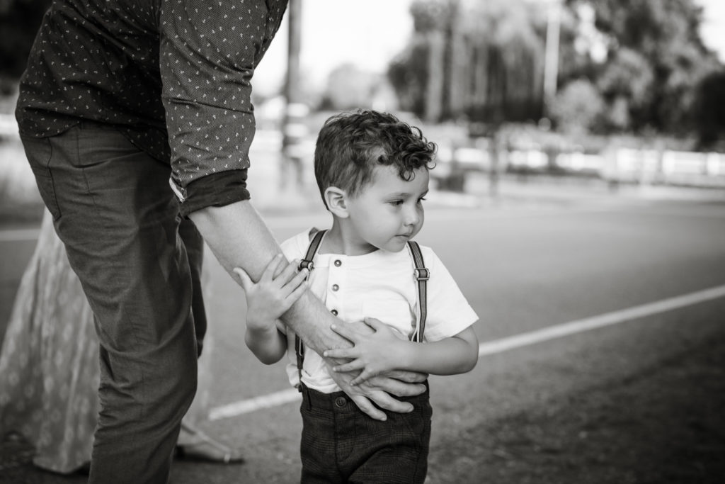 Fathers hand protectively keeps toddler boy safe near the street during family photo session