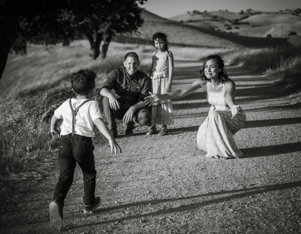 Little boy runs to his mother's outstretched arms during family photo session in the Livermore hills